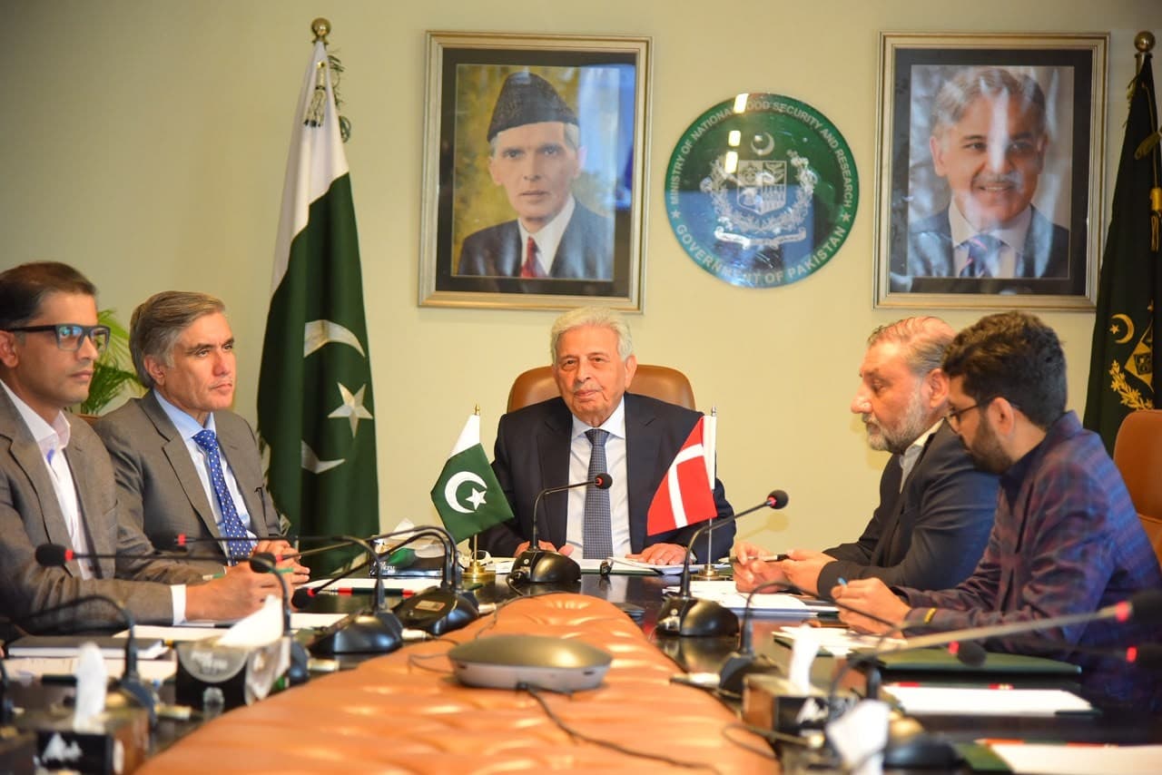 Federal Minister Rana Tanveer Hussain chairs the Ministry of National Food Security and Research meeting on the Pakistan–ICARS memorandum, with the flags of Pakistan and Denmark on the table.