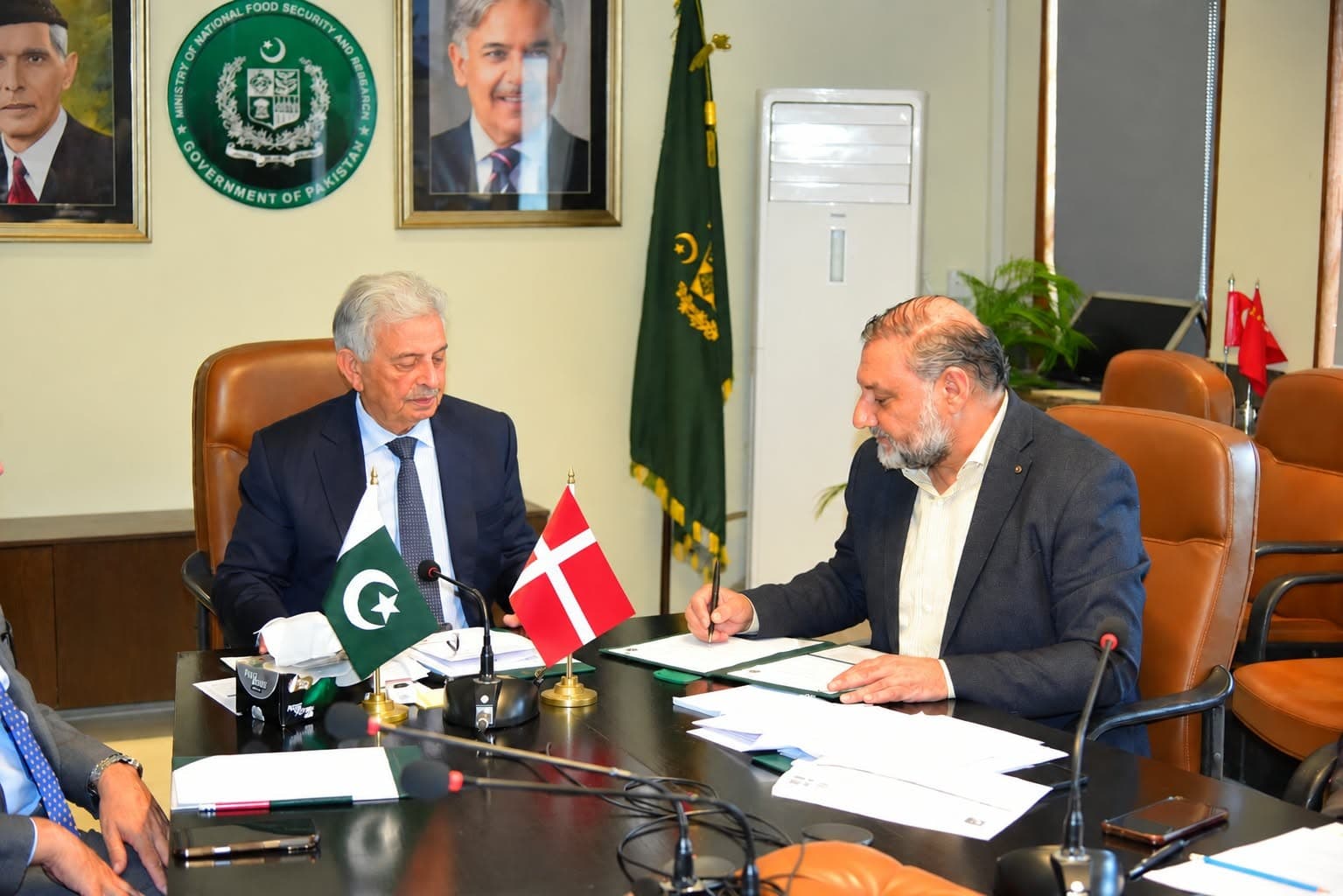 Documents being signed at the Ministry of National Food Security and Research during the Pakistan–ICARS engagement, with the flags of Pakistan and Denmark on the table.